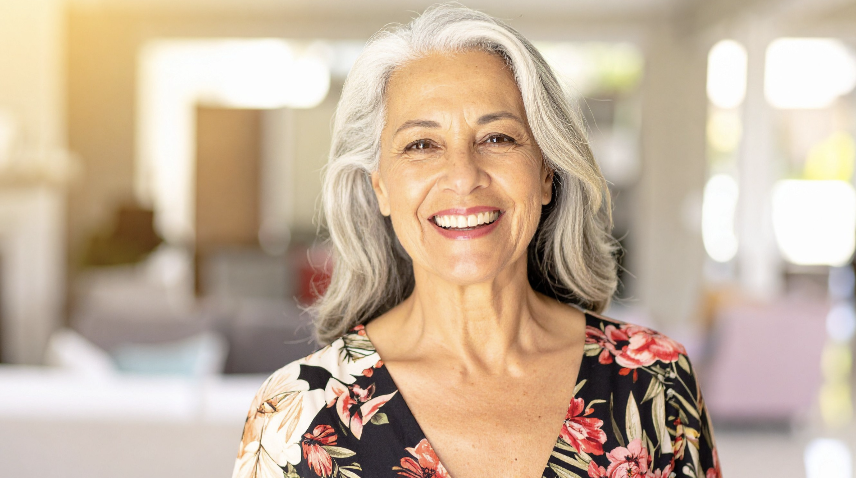 Senior woman smiling warmly while using a tablet at home